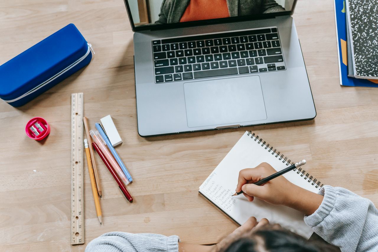 the hand of a person taking notes in front of a notebook during a video call